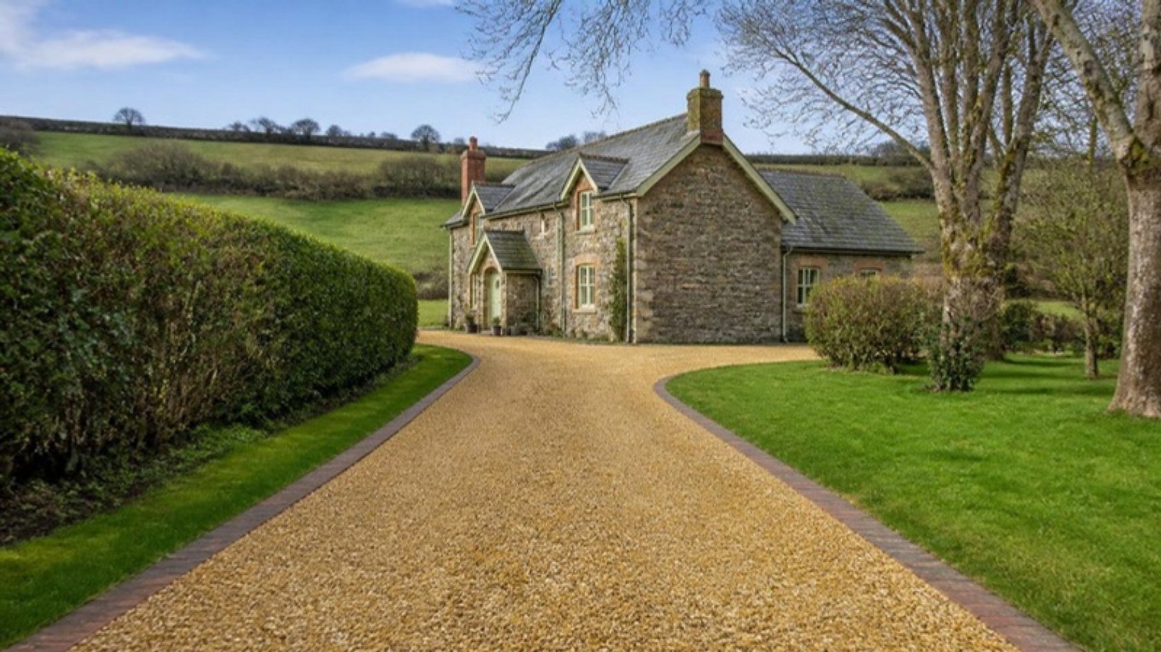 Gravel driveway leading up to a stone farmhouse in the Welsh countryside